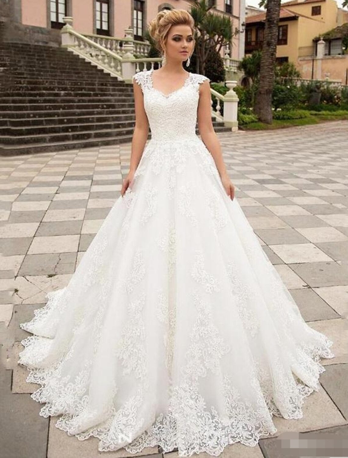 Elegant white lace ball gown wedding dress with illusion neckline and cap sleeves.