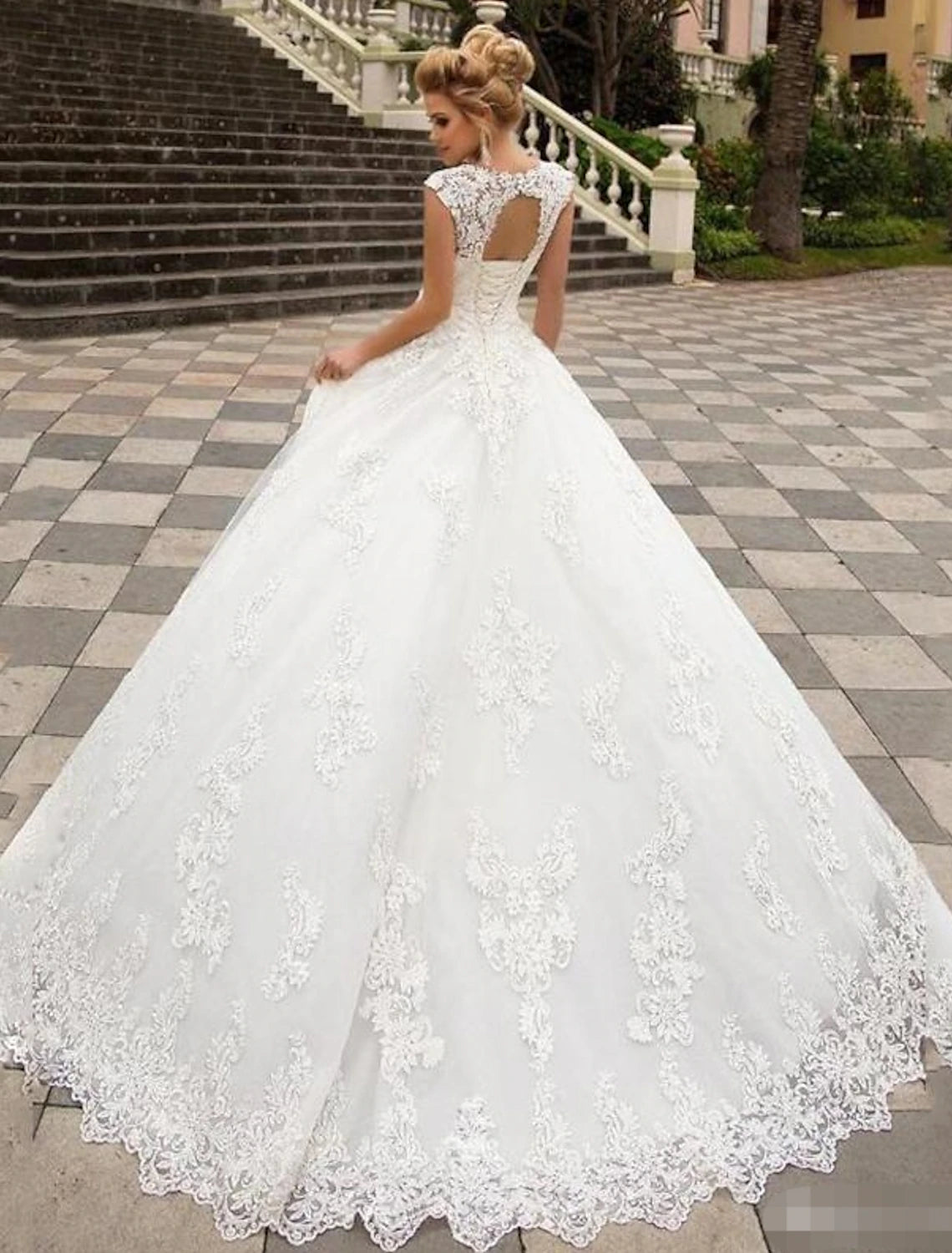 Back view of a white bridal ball gown showing open back and lace appliques.