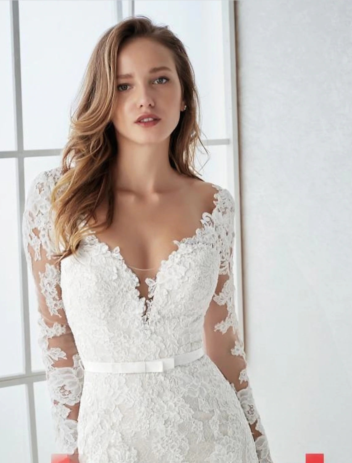 Elegant lace mermaid trumpet wedding dress with V-neck, long sleeves, and open back.
