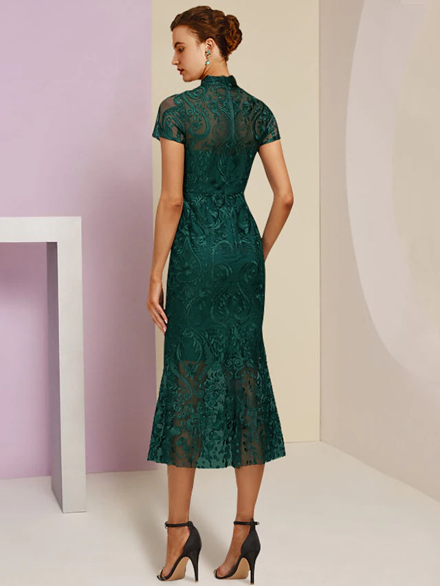 Side view of a woman in a high neck, short sleeve, tea length lace sheath dress.