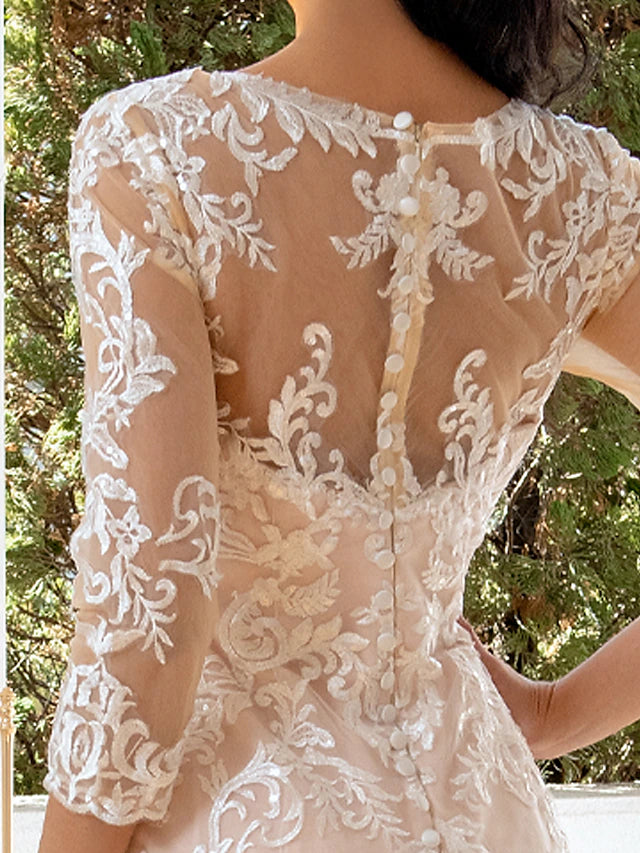 Woman posing in a formal long sleeve lace wedding dress.