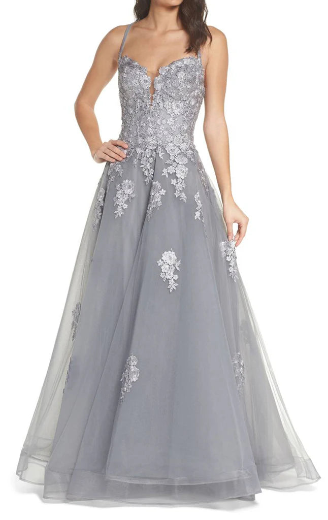 Woman wearing an elegant lace and tulle long prom gown with spaghetti straps.