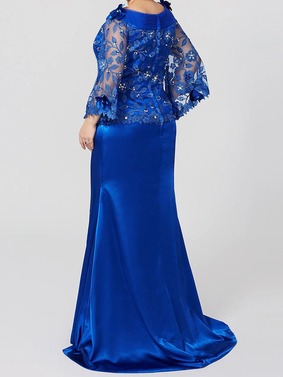 Woman showcasing the back detail of a mermaid applique mother of the bride gown.