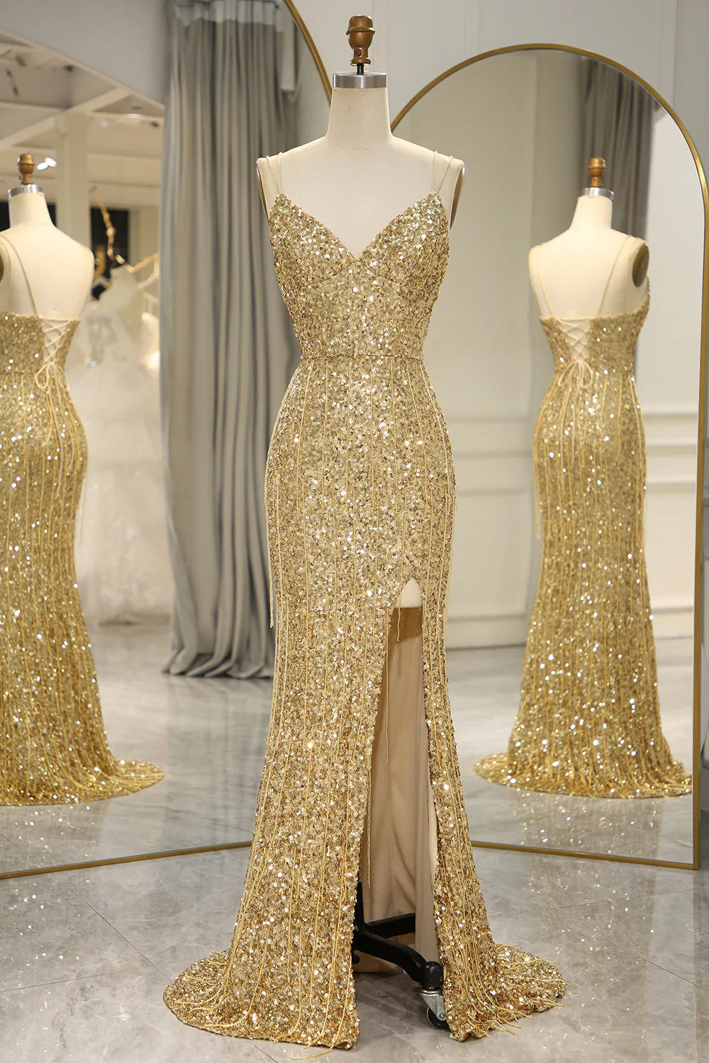 Model wearing an elegant golden mermaid backless prom dress with a high slit.