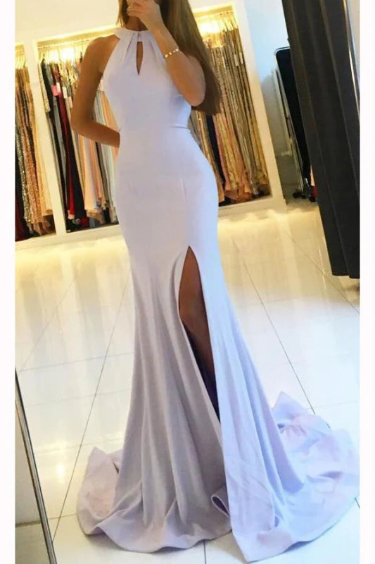 Woman wearing an elegant mermaid backless long prom dress with a high leg split.