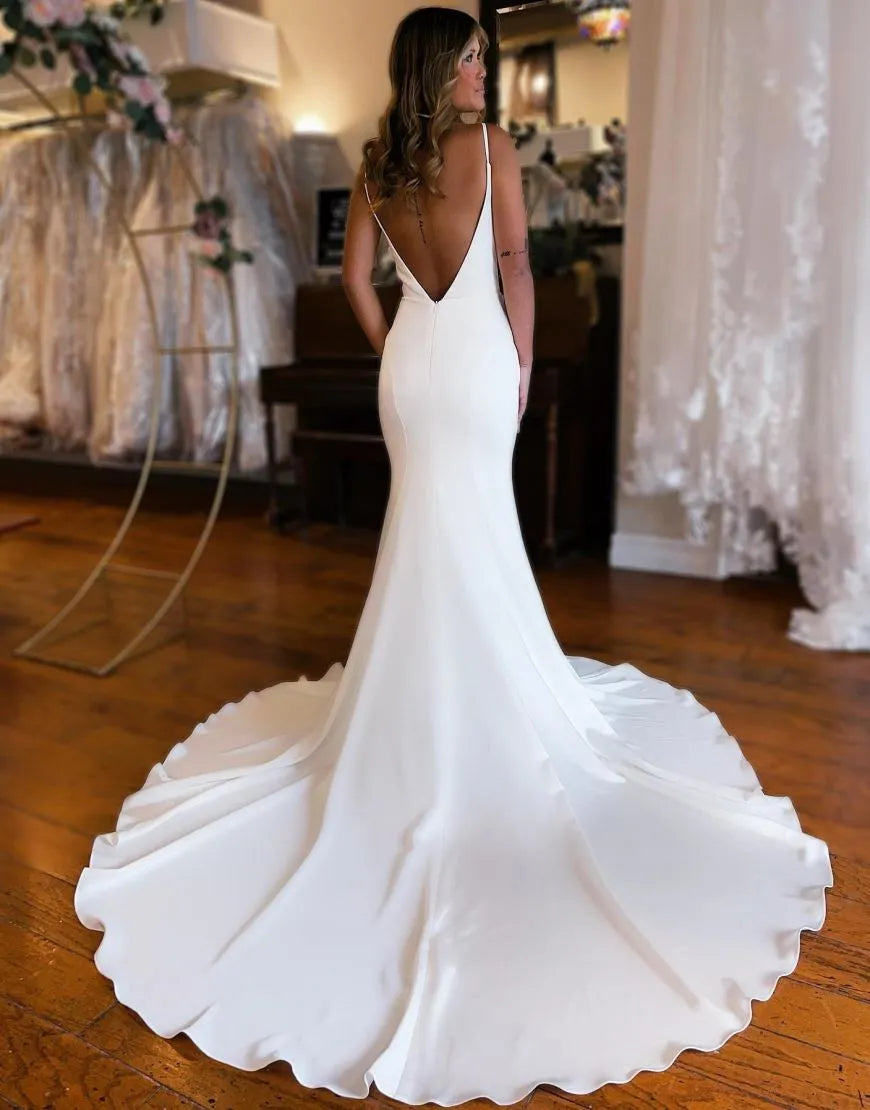 Back view of a mermaid satin wedding dress featuring an open back and long train.