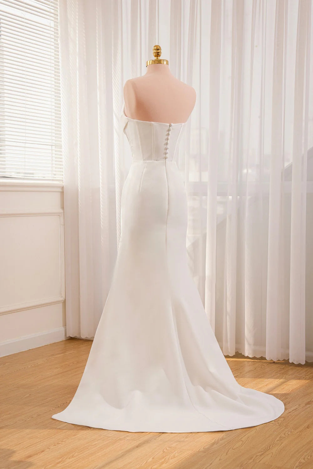 Back view of a mermaid satin wedding dress with a flowing train.