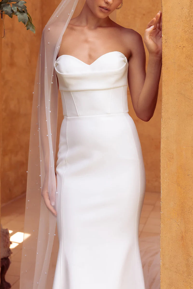 Close-up of the sweetheart neckline and pleated satin fabric on the wedding dress.