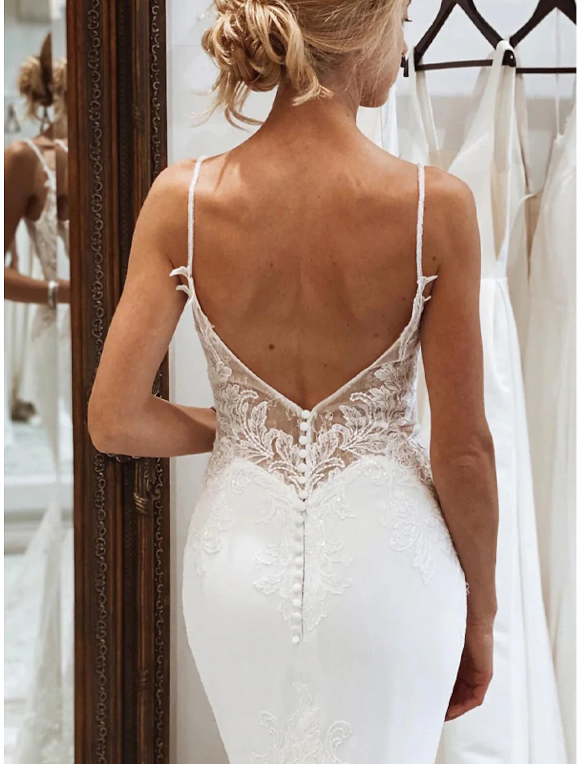 Side profile of white mermaid bridal gown with camisole neckline and appliques.