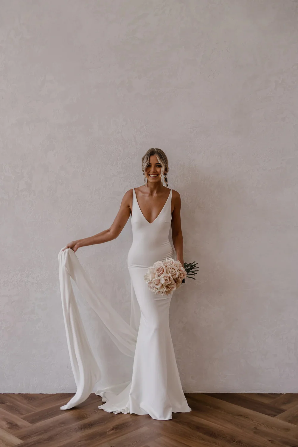 Full view of an elegant white mermaid wedding dress with a deep V-neck and open back.