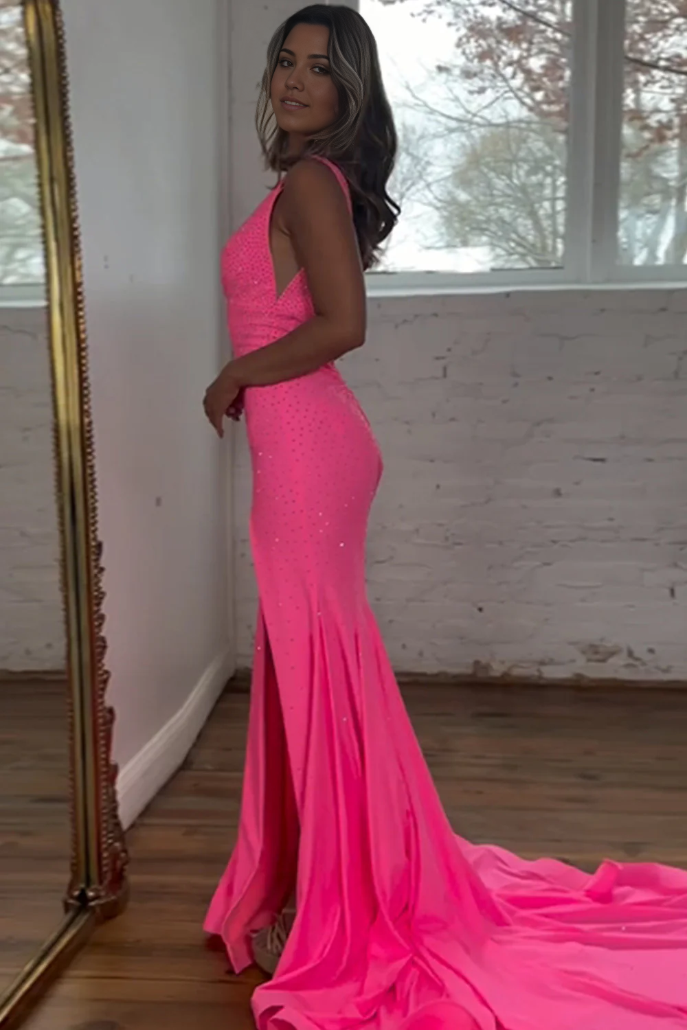 Woman posing in a mermaid deep V-neck open back long beaded formal dress.
