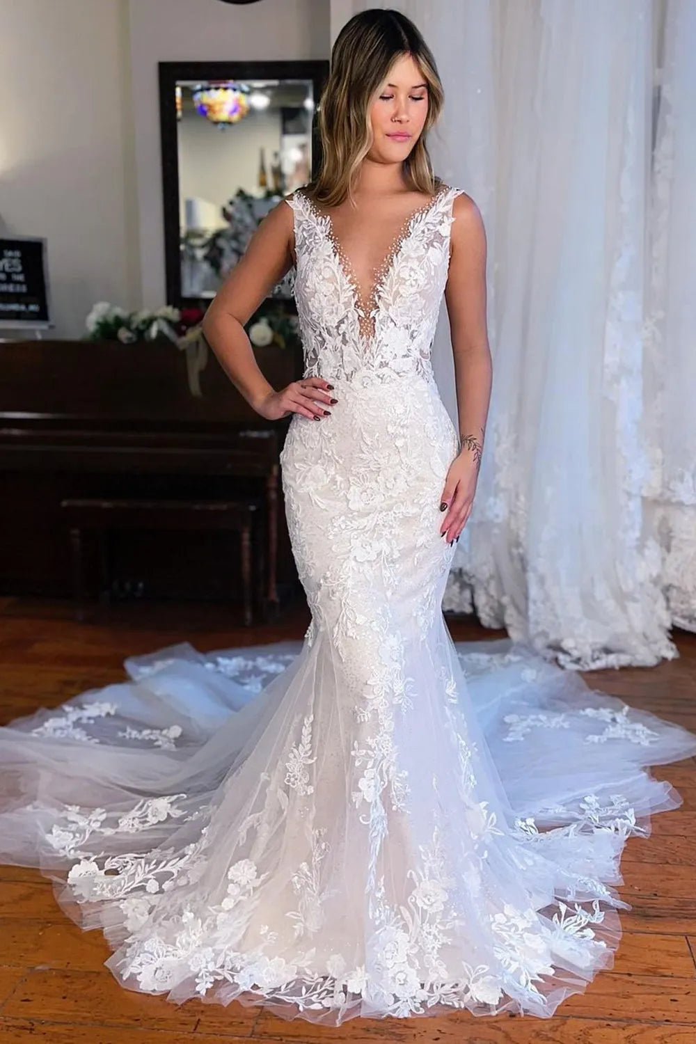 Elegant mermaid deep V-neck lace wedding dress with a sweep train, front view.