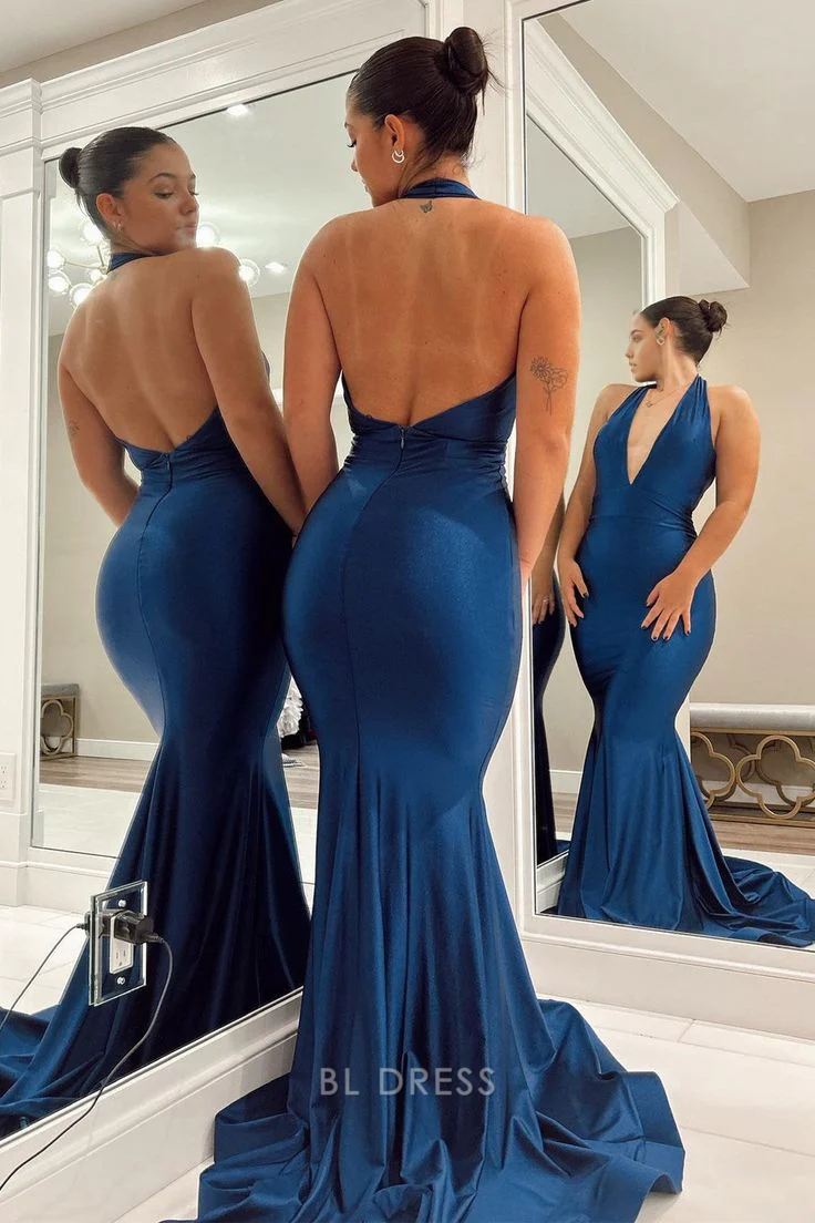 Back view of a woman in a navy blue mermaid halter backless gown.