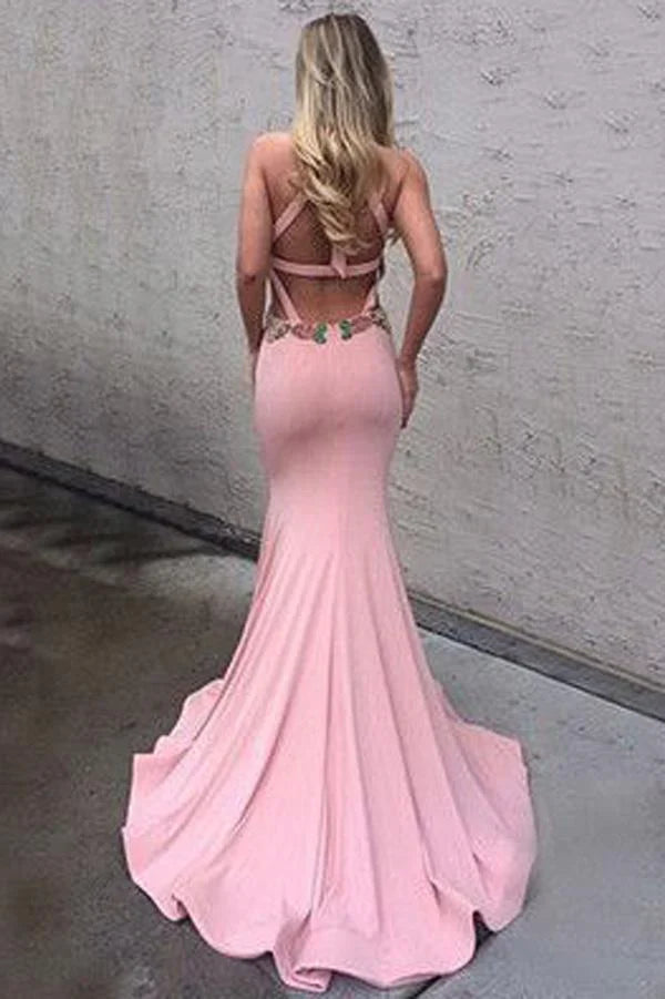 Back view of a woman wearing an elegant dark mermaid halter open back long prom dress.