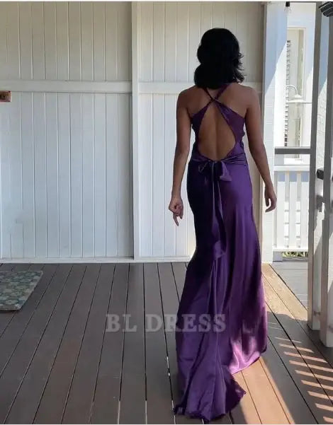 Side view of a woman wearing a purple mermaid halter V-neck satin long formal dress.