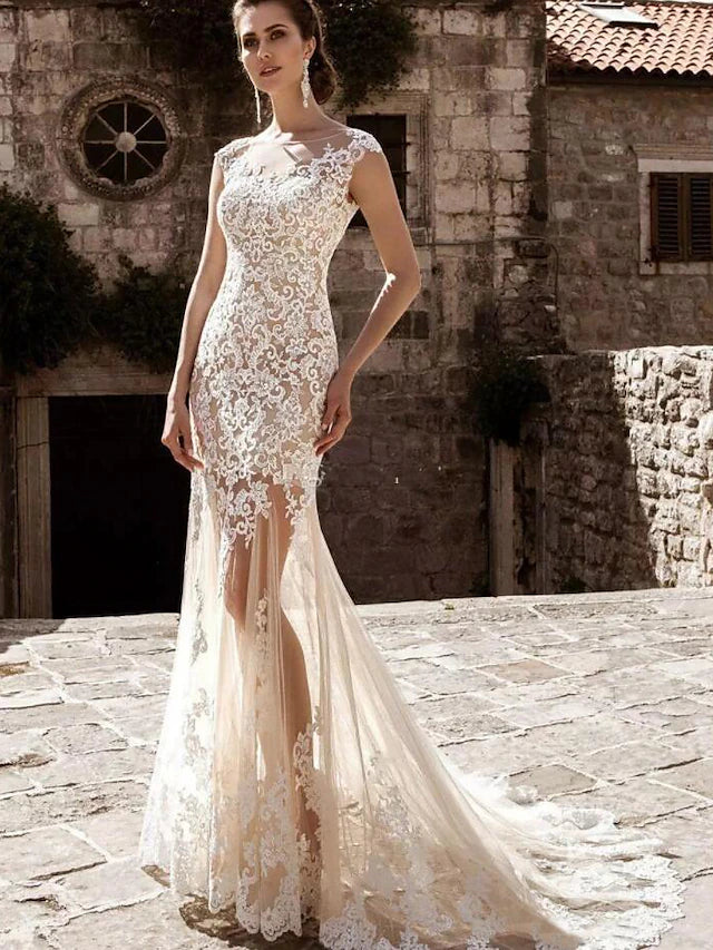 Side view of a bride in a white mermaid wedding dress, showcasing the lace appliques and court train.