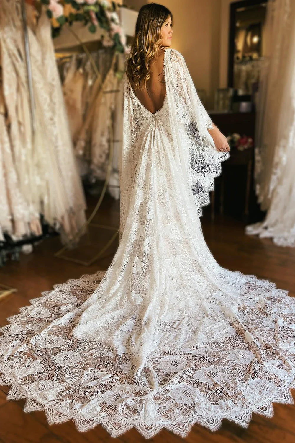 Side view of an ivory mermaid wedding dress showcasing the lace sleeves and graceful cape.