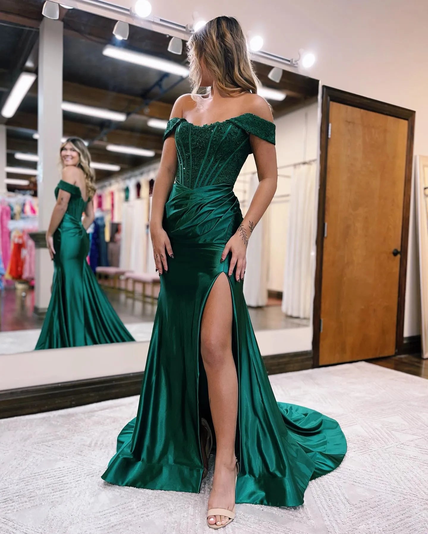 Woman in an elegant dark mermaid off-shoulder long dress with a court train and high split.