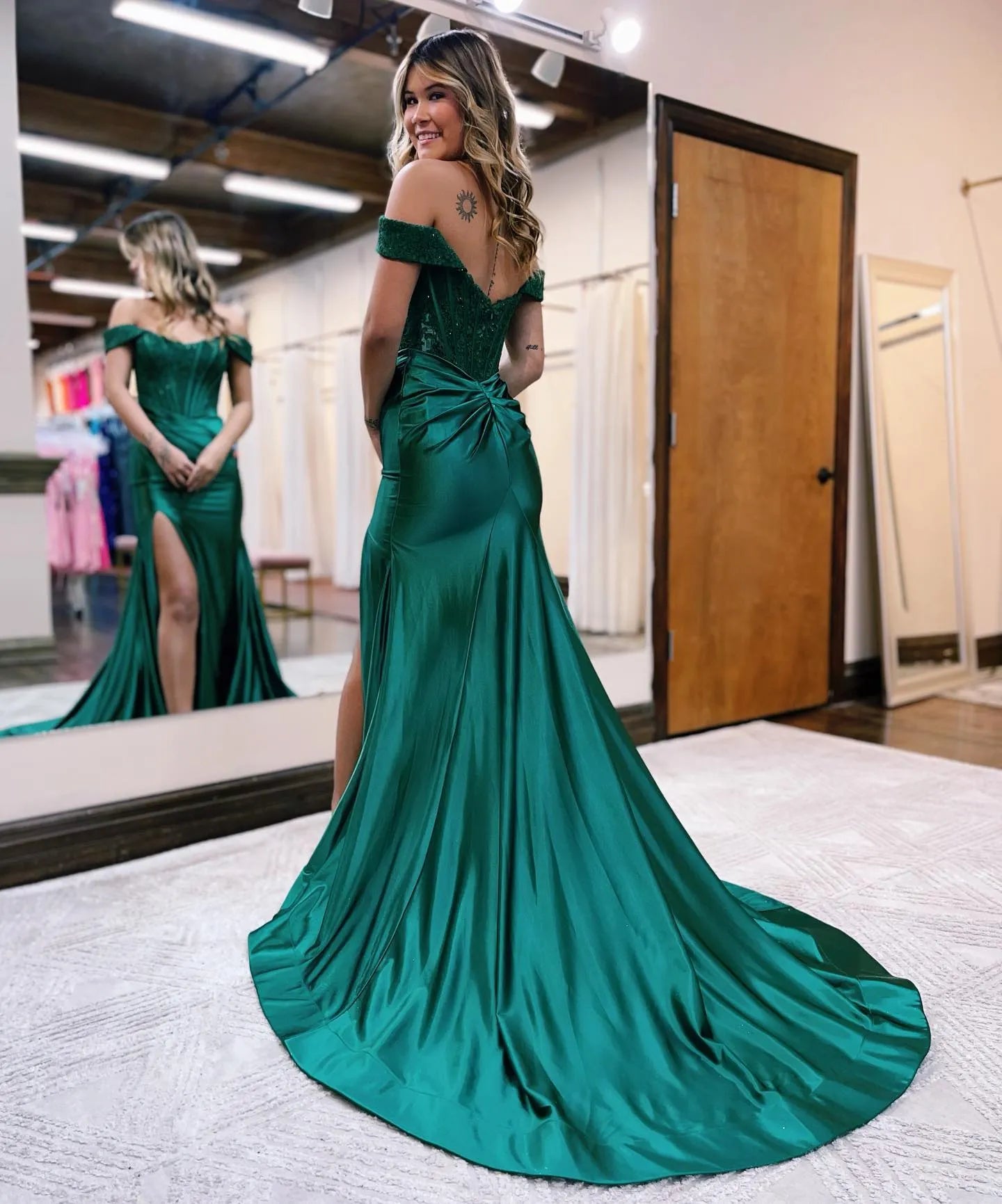 Woman posing in a dark mermaid off-shoulder gown, showcasing the high split.