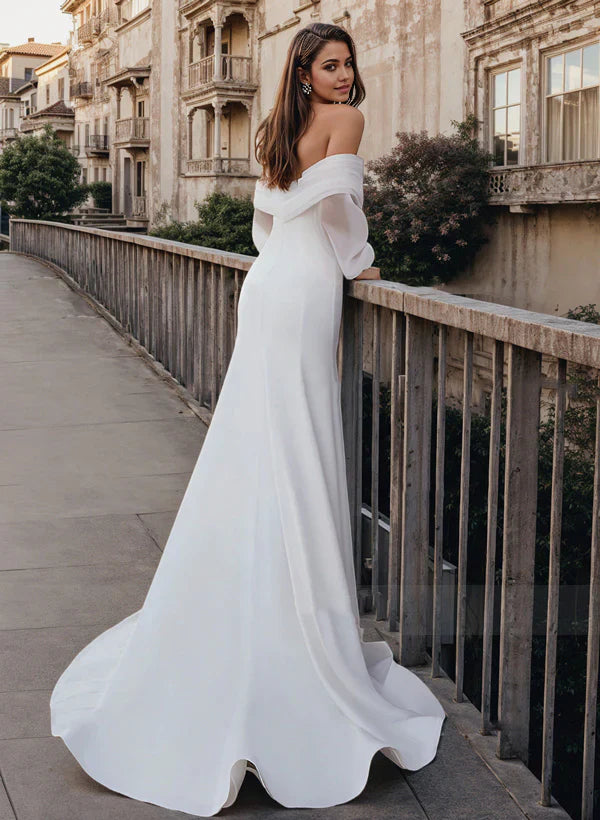 Back view of a mermaid off-shoulder long sleeve satin wedding dress with a flowing train.