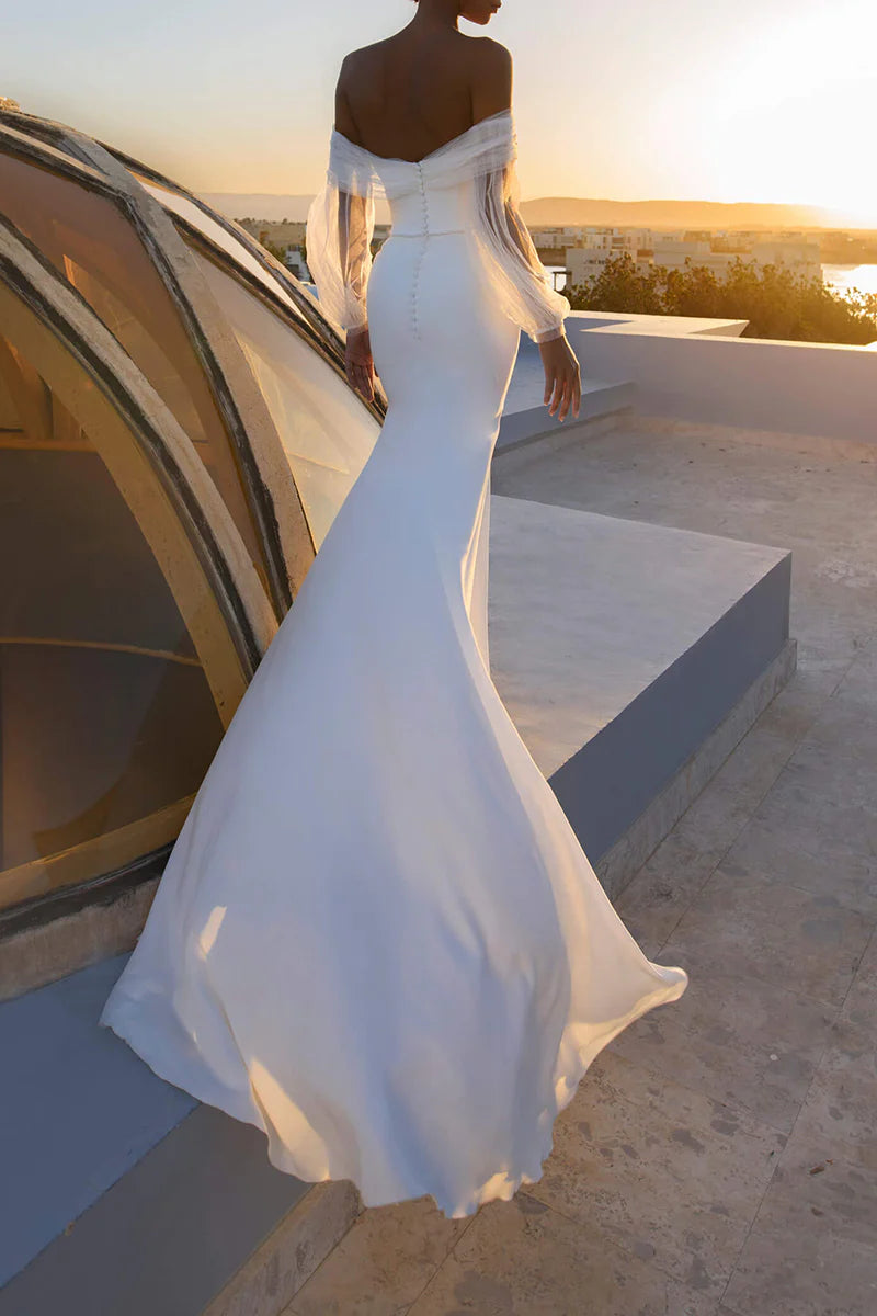 Mermaid wedding dress with off-shoulder neckline and long sleeves, side view.
