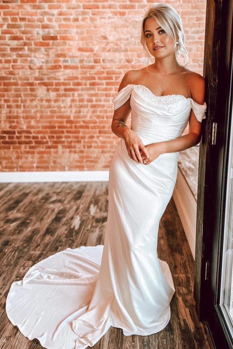Full view of an elegant mermaid off-shoulder wedding dress with pearl embellishments.