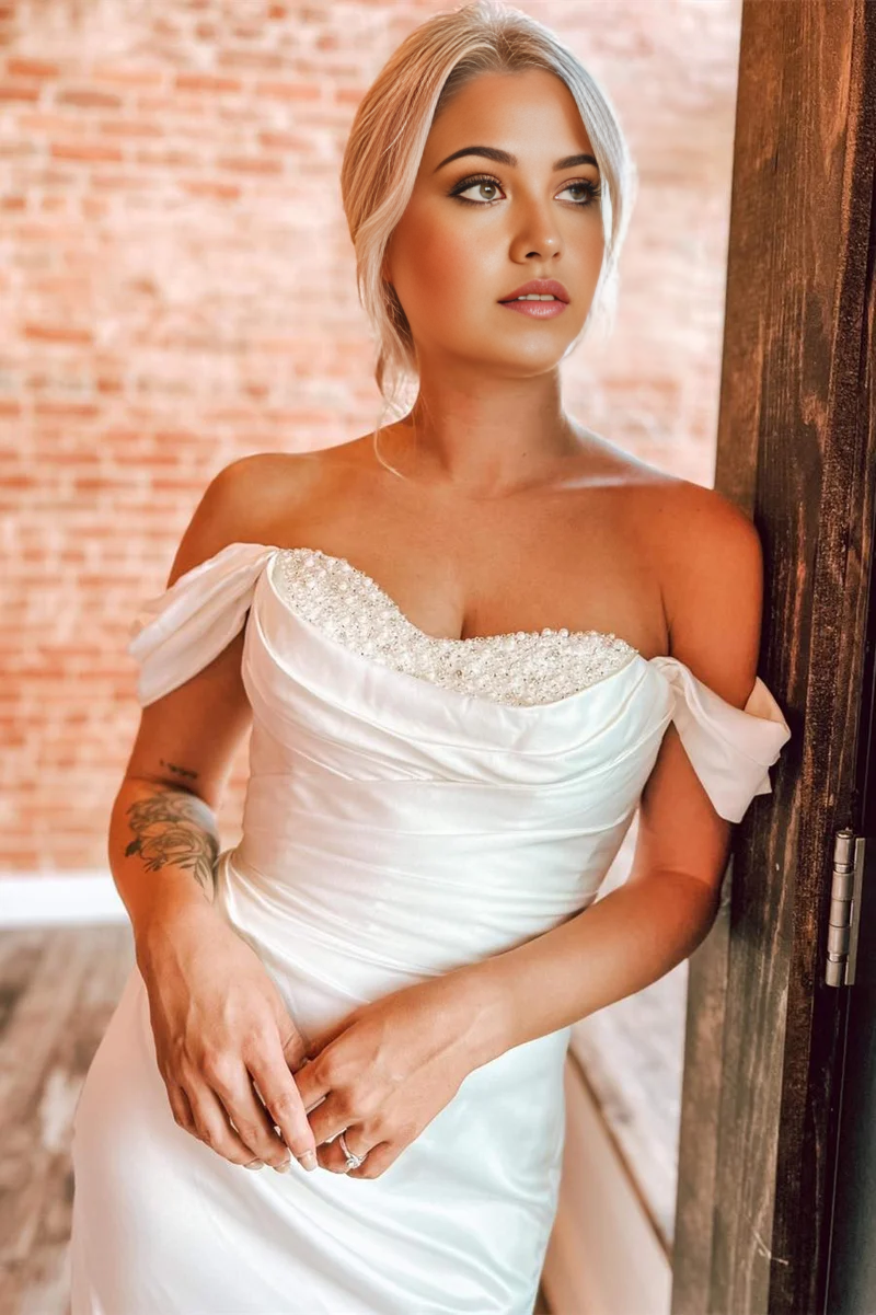 Close-up of delicate pearl details on the off-shoulder neckline of the wedding dress.