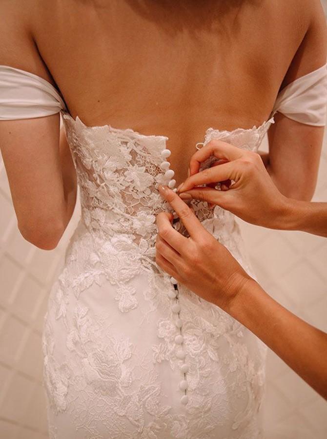 Side view of off-shoulder mermaid bridal gown with intricate lace appliques.