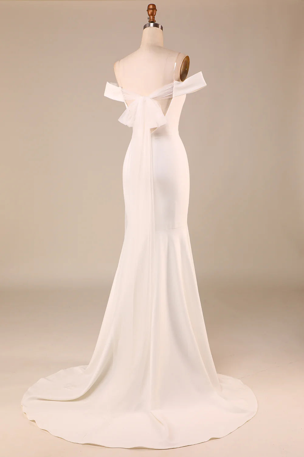 Back view of an ivory mermaid wedding dress, highlighting the large bownot and off-shoulder design.