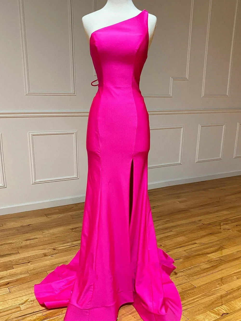 Side profile of a woman wearing a mermaid one-shoulder long prom dress, highlighting the silhouette.