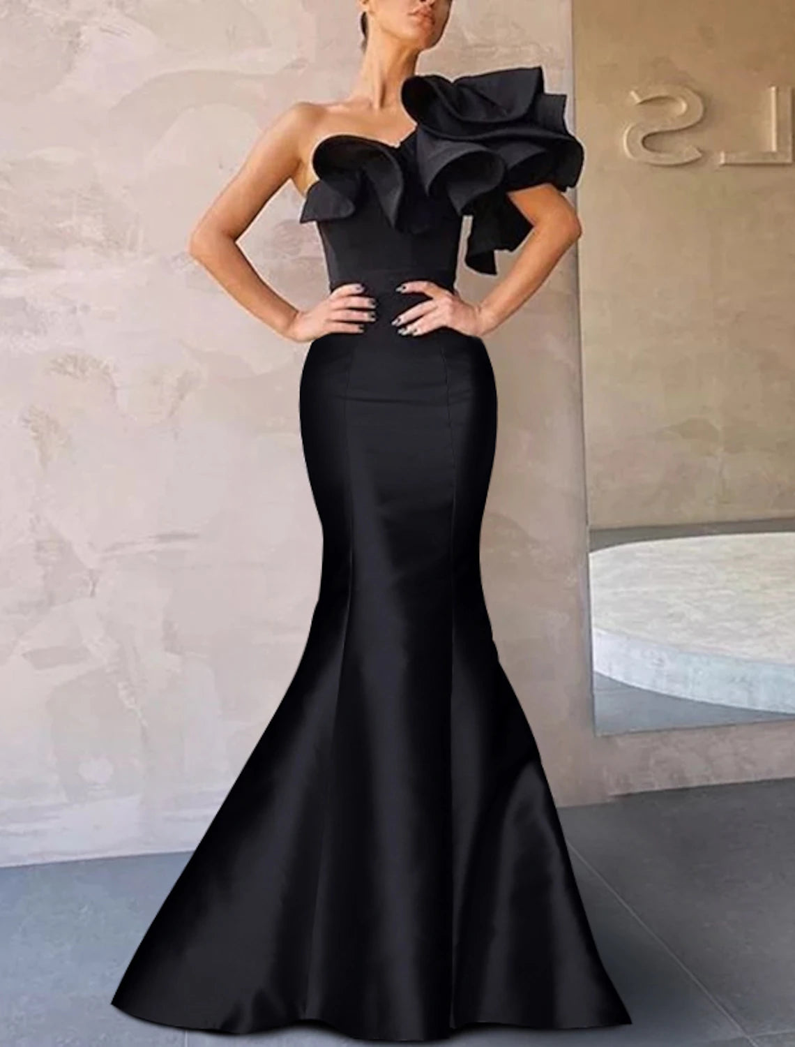 Side view of a woman posing in a formal mermaid gown.