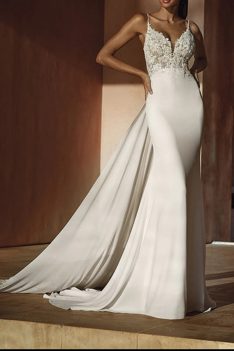Model wearing a white mermaid wedding dress with plunging V-neck and lace appliques.
