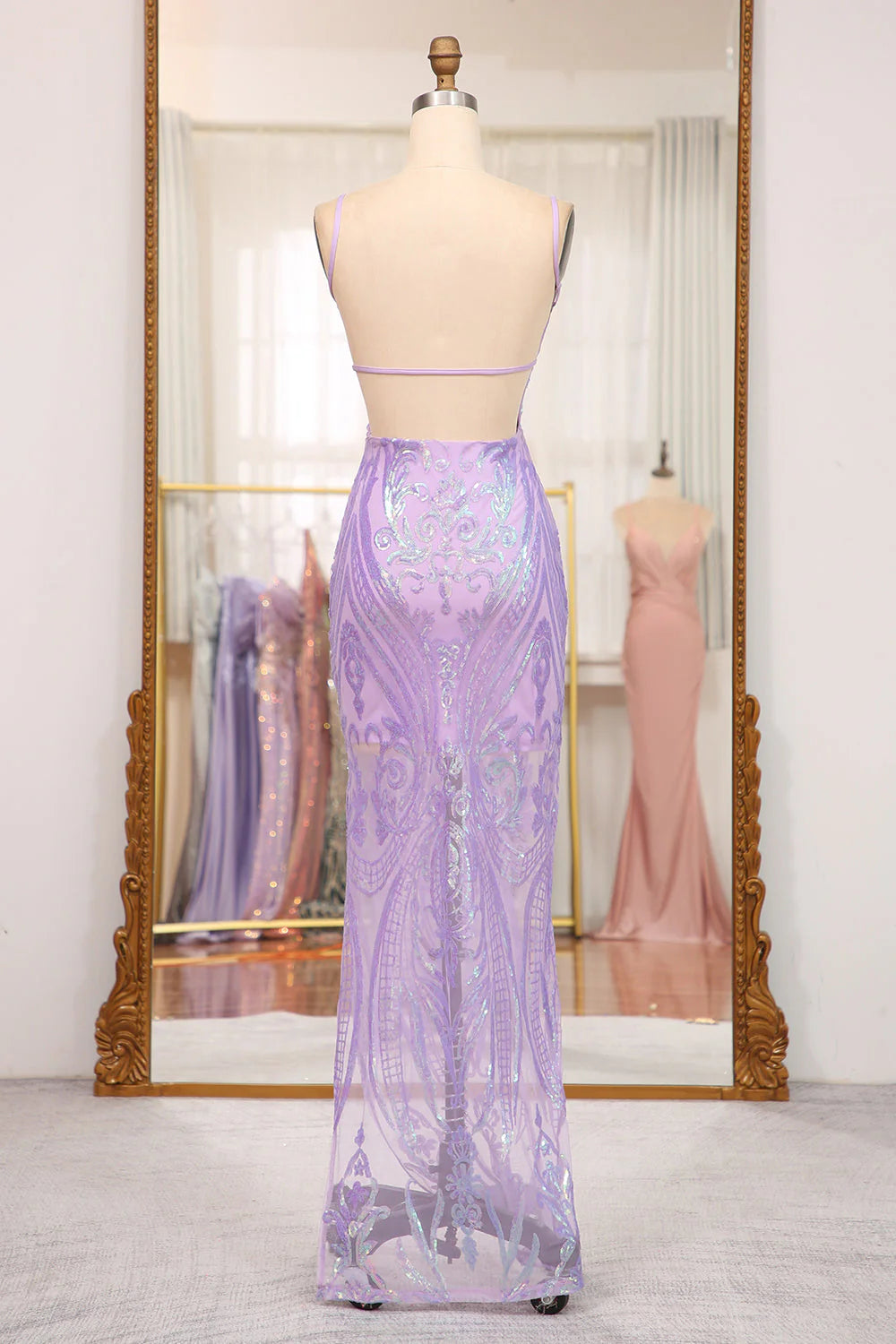 Back view of a model in a backless mermaid prom dress with spaghetti straps.