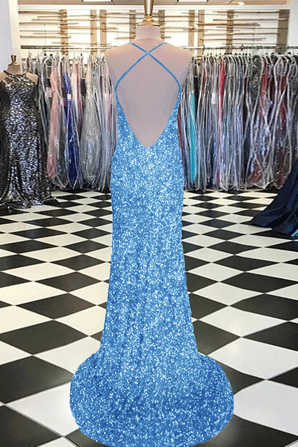 Woman in a dark blue mermaid sequin prom dress, posing with hands on hips.