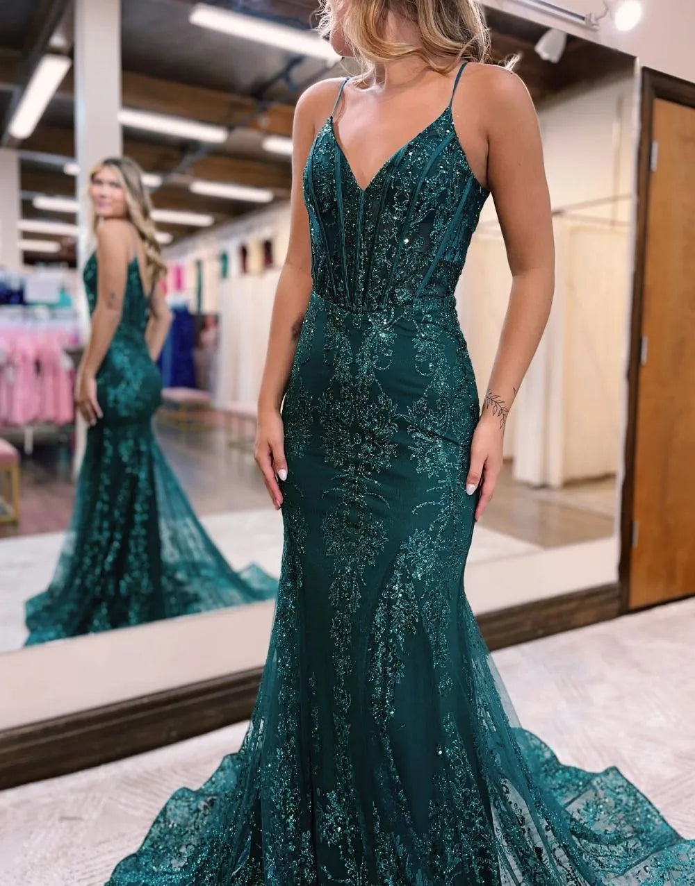 Side view of peacock blue mermaid gown, showcasing appliques and flowing silhouette.