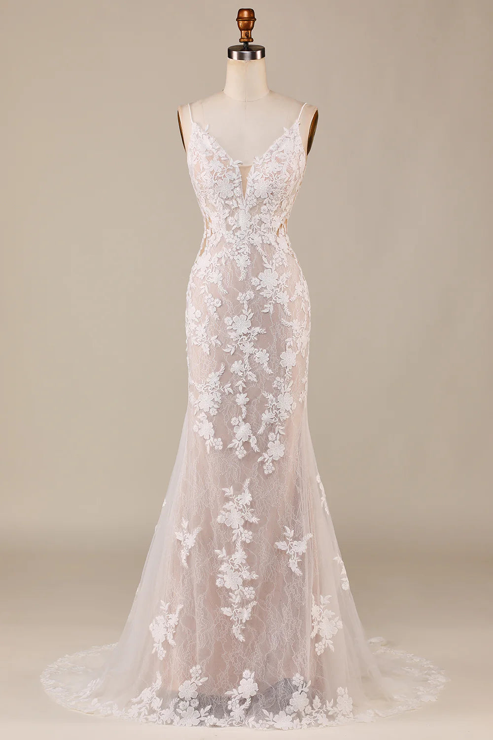 Model wearing an elegant ivory mermaid wedding dress with spaghetti straps and intricate appliques.