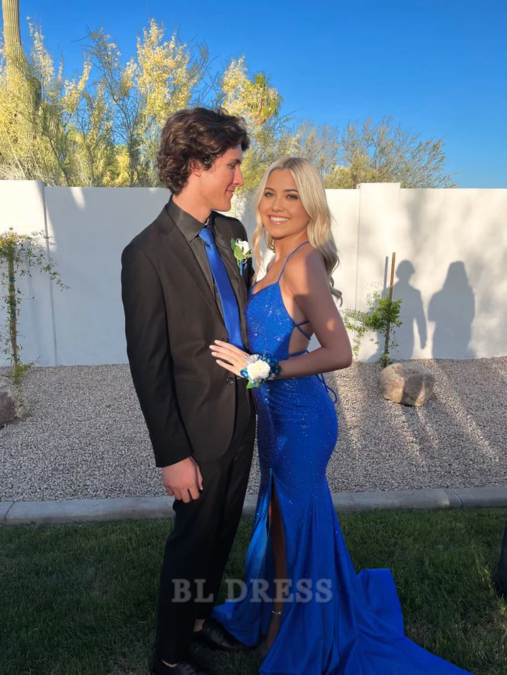 Woman wearing an elegant blue mermaid formal dress with spaghetti straps and a high slit.