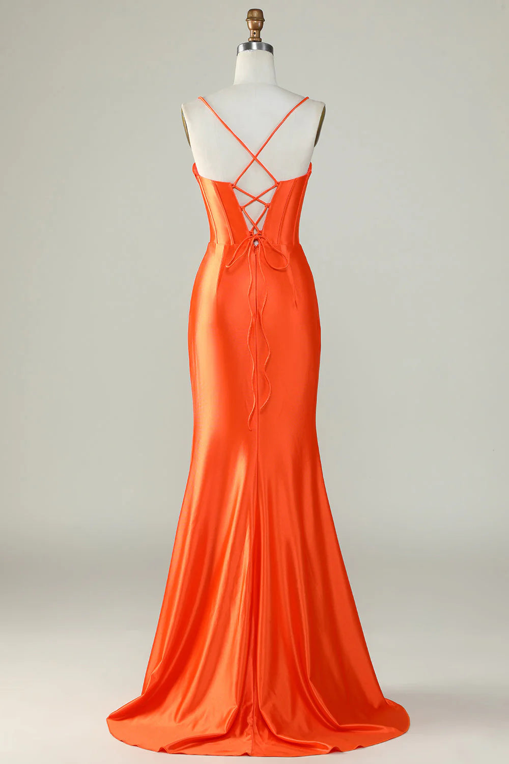 Side view of an orange mermaid formal gown with spaghetti straps.