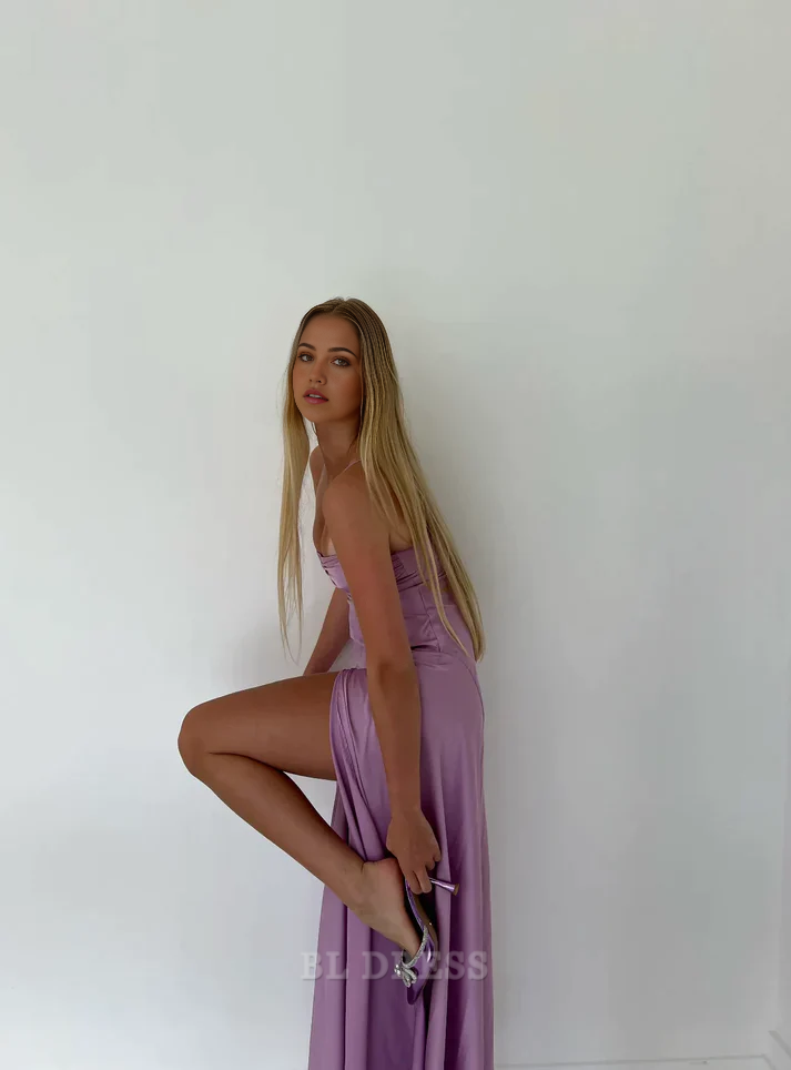 Model wearing a purple mermaid formal gown with spaghetti straps and a high split.
