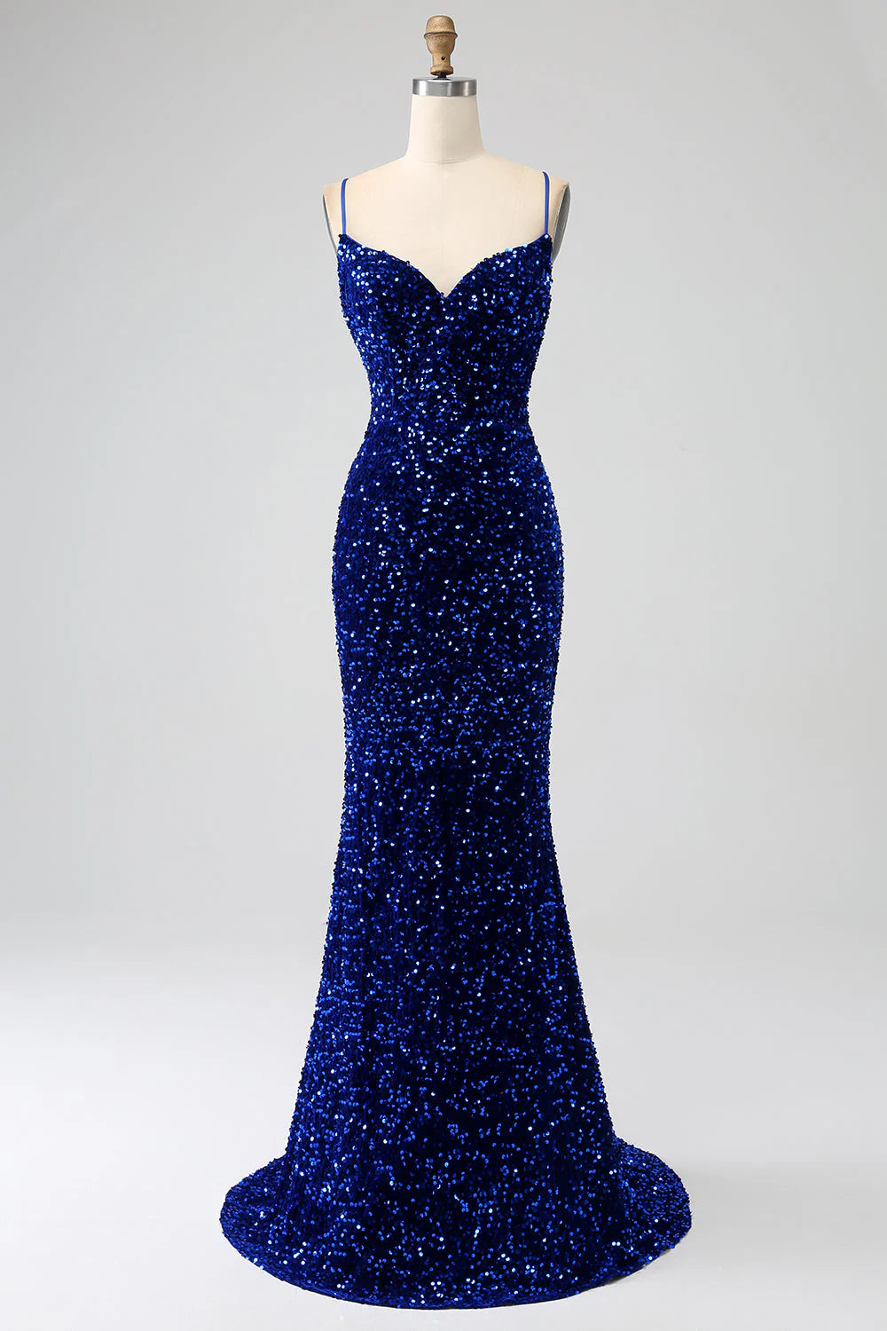 Woman wearing a royal blue mermaid prom dress with spaghetti straps and sequin details.