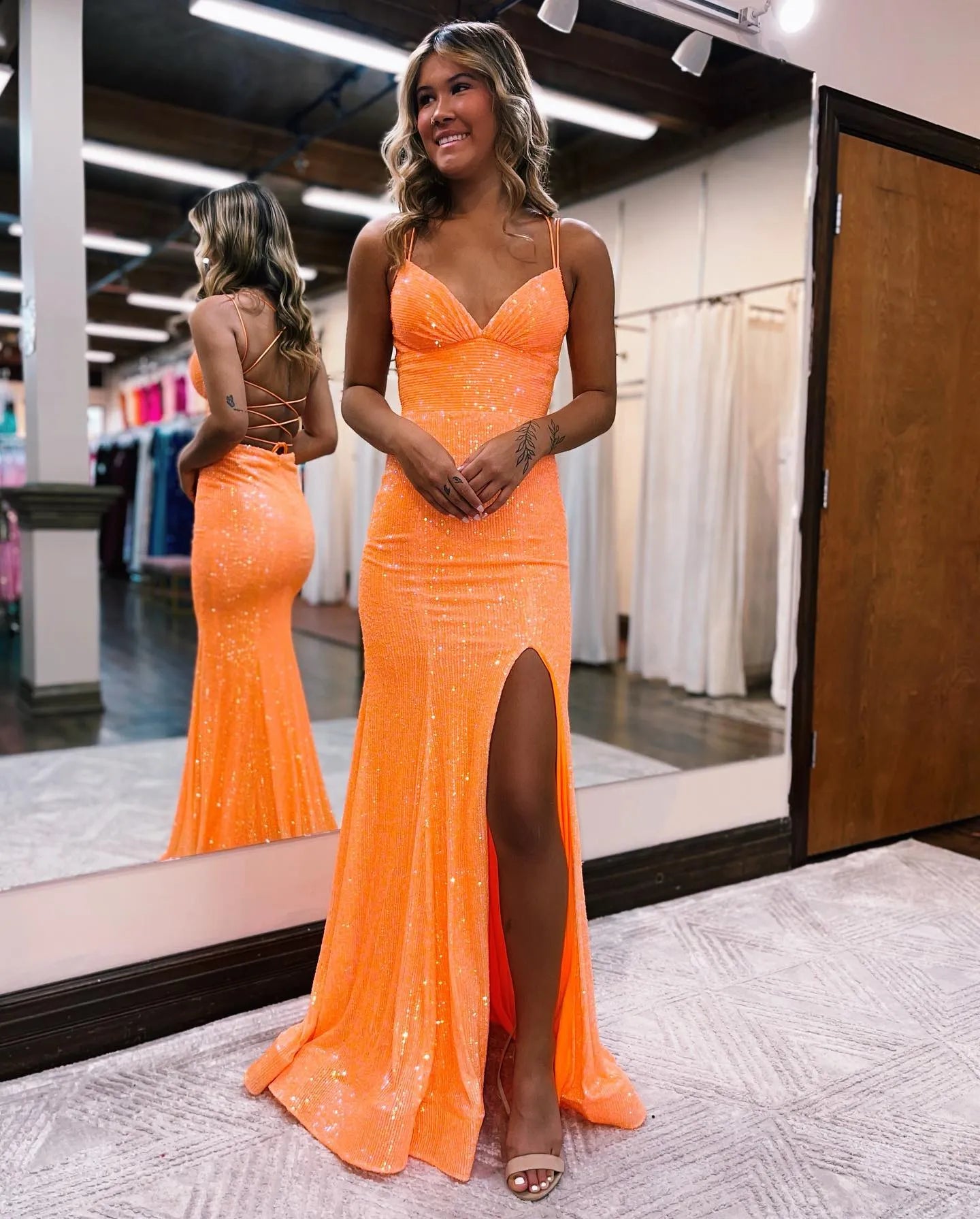Side view of a woman posing in a mermaid prom dress, showing the lace detail and split.