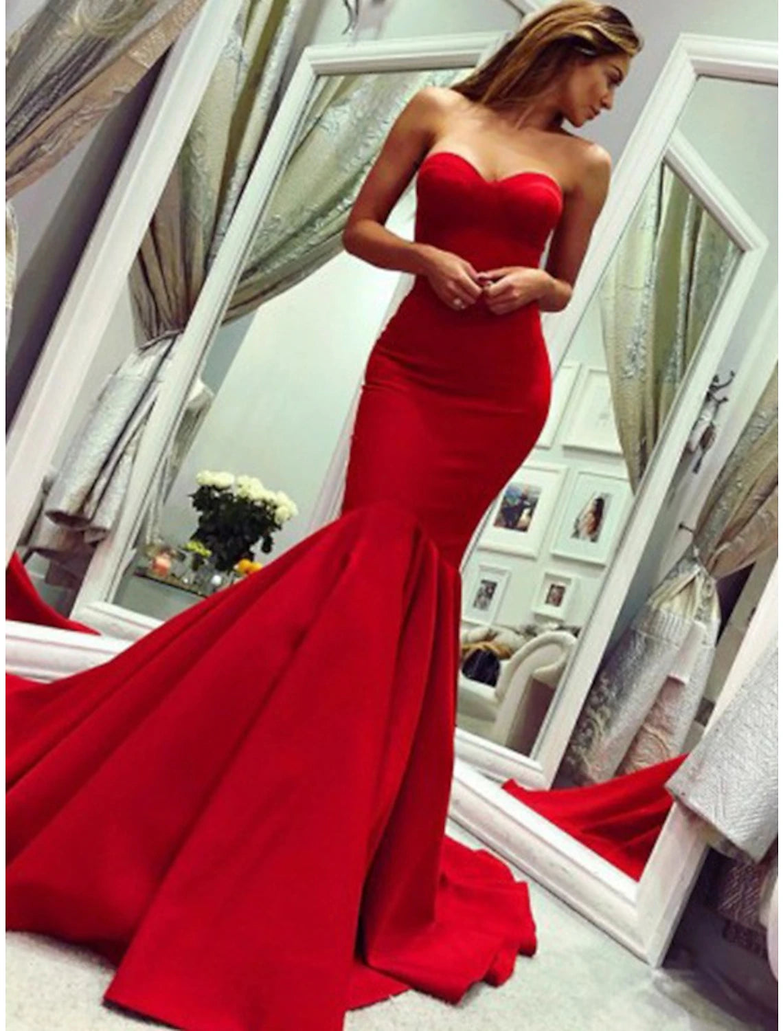 Woman posing in an elegant strapless mermaid evening gown with pleats and a court train.