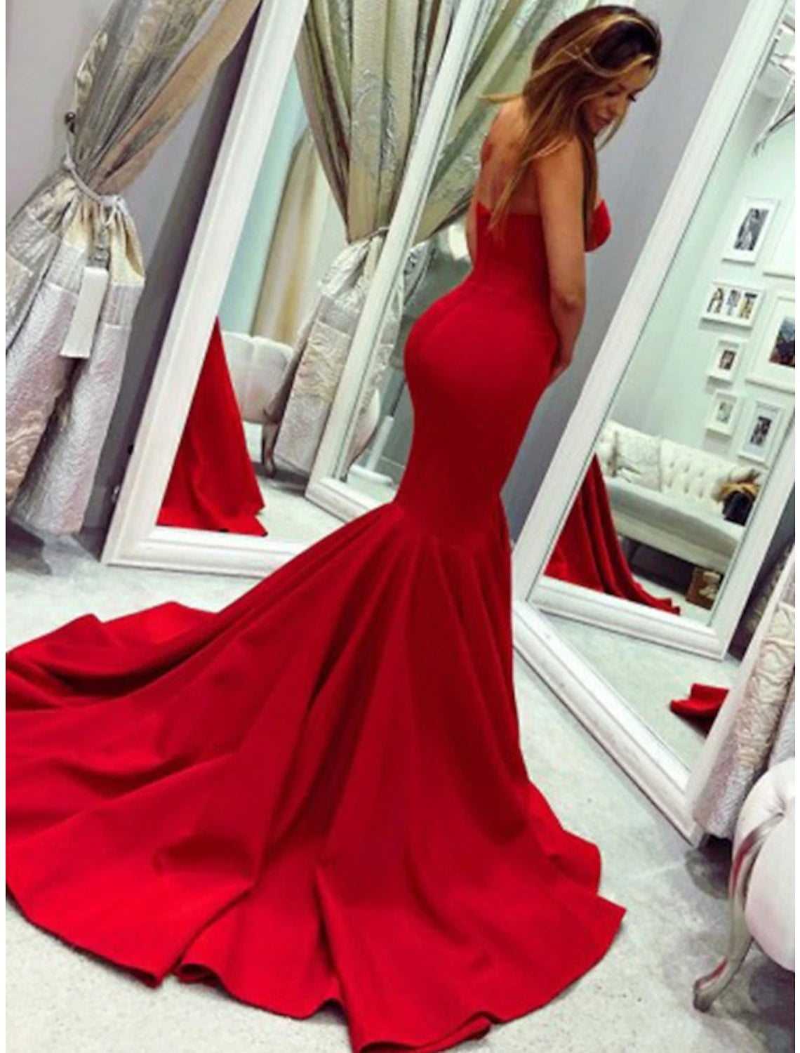Side view of a woman in a pleated strapless mermaid dress, showcasing the court train.