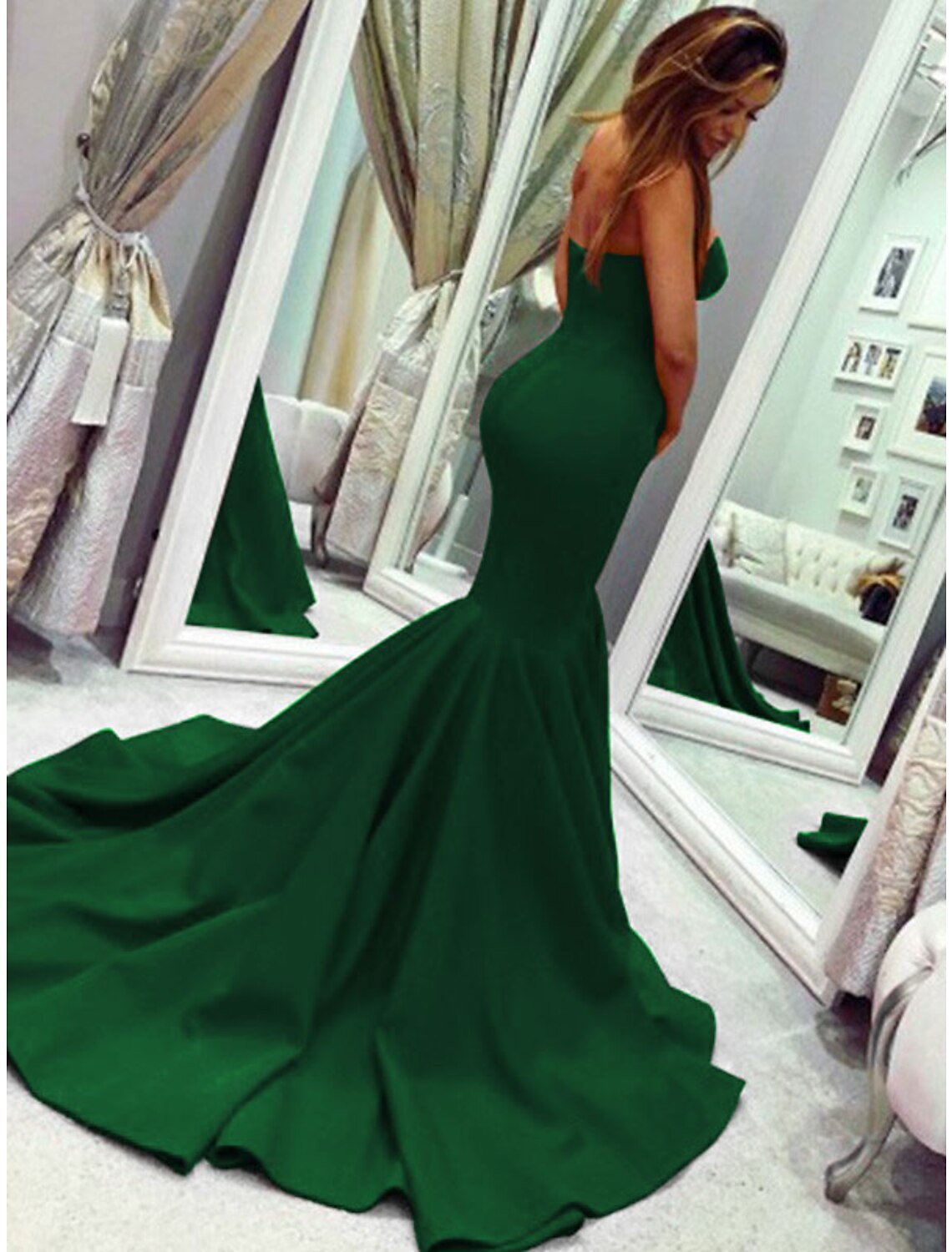 Woman in a strapless mermaid dress, seated gracefully, highlighting the skirt's flare.