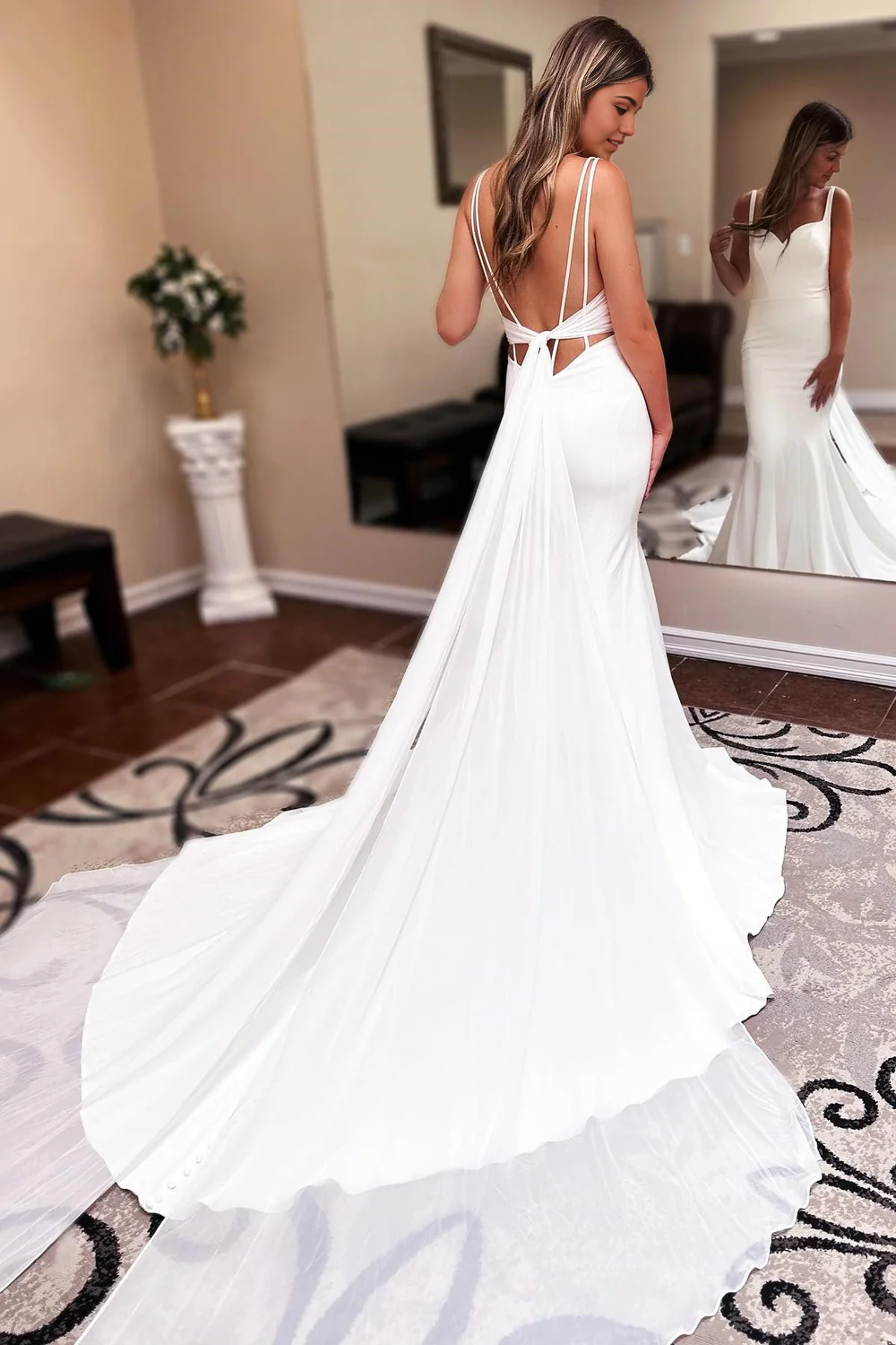 Back view of a mermaid wedding dress showcasing the backless design and long train.