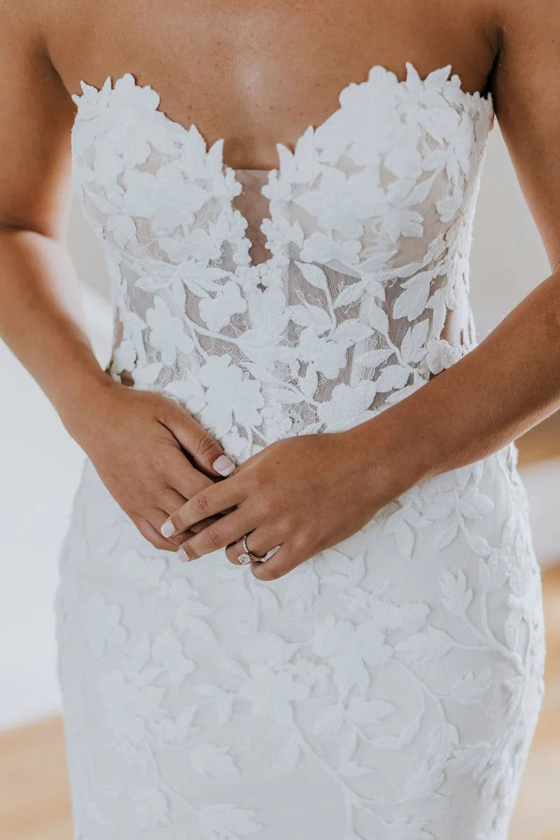 Close-up of the sweetheart neckline and long tulle sleeves with applique details on a bridal gown.