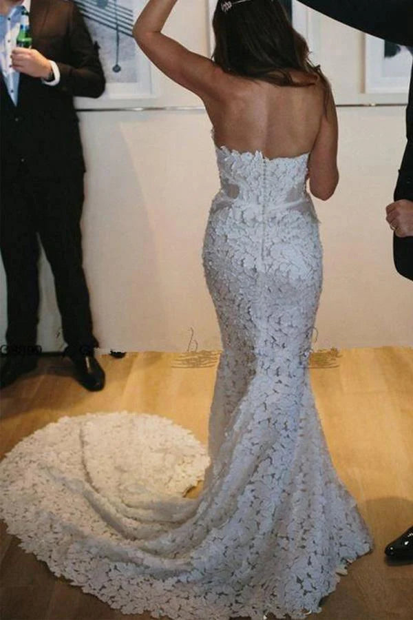 Back view of a mermaid bridal gown with a sweep train, showcasing lace embellishments.
