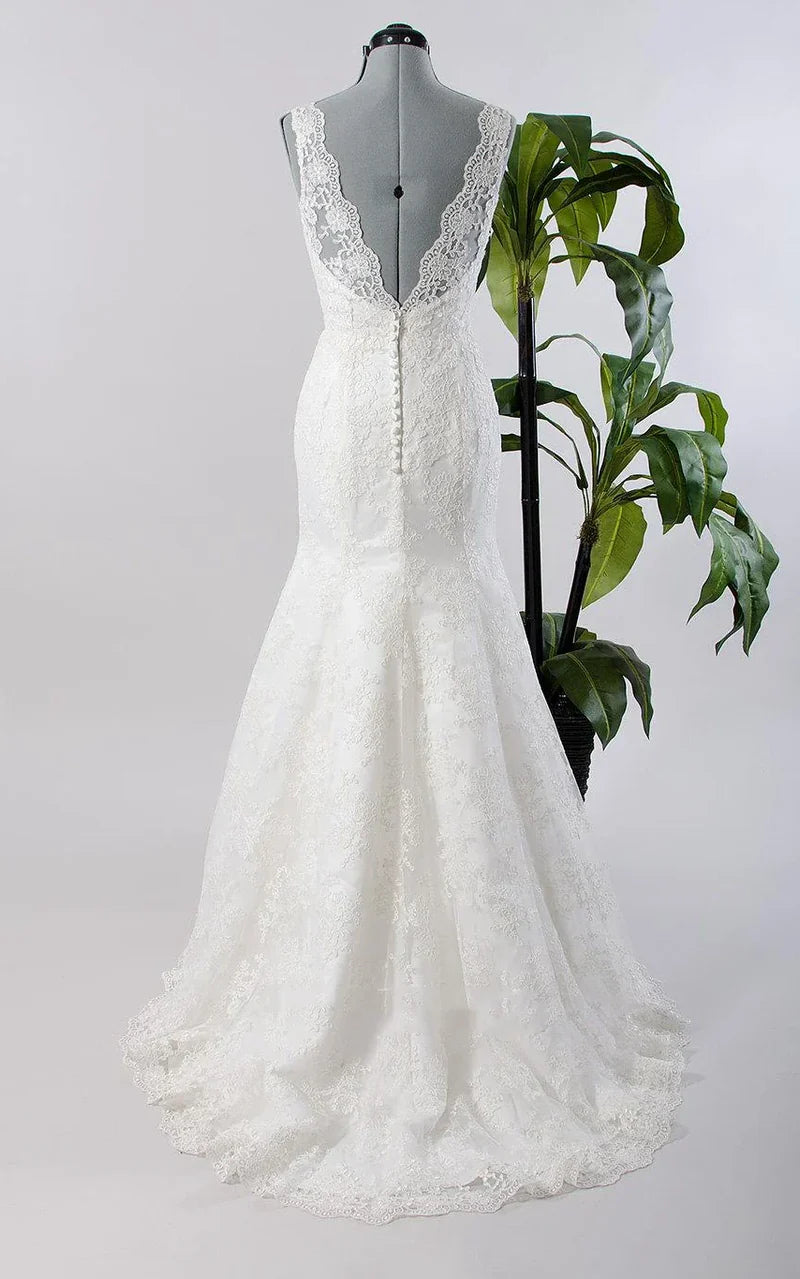 Back view of a woman in a mermaid-style formal dress, showcasing the intricate lace and flowing tulle train.