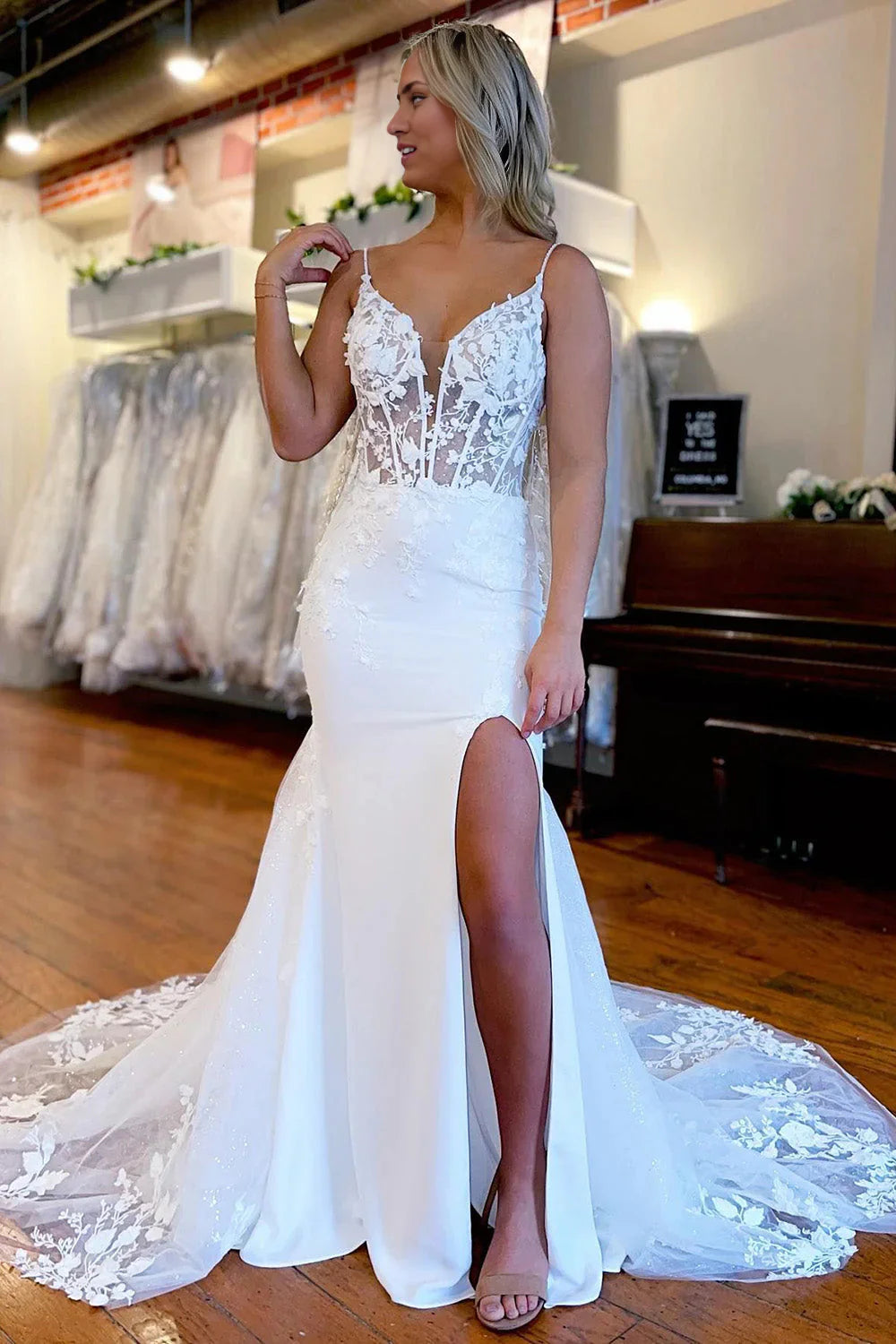 Mermaid wedding dress with spaghetti straps, high slit, and appliques on a model.