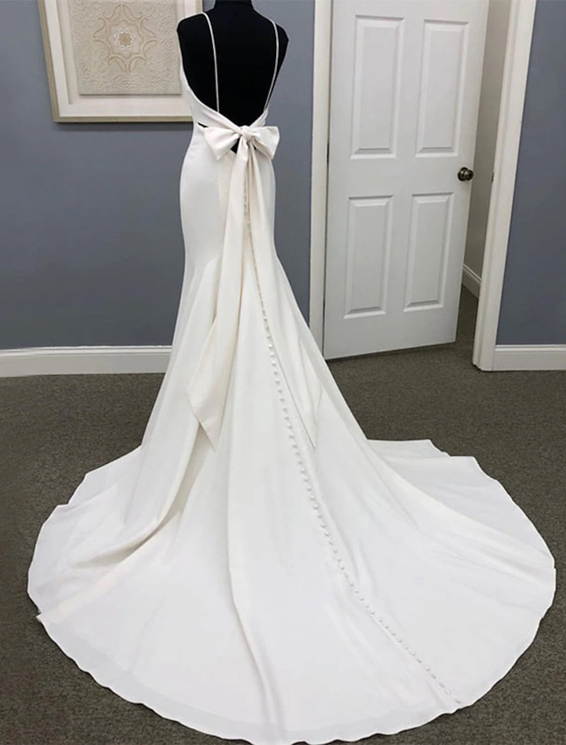 Side view of a satin mermaid bridal gown, showcasing the court train and bow detail.